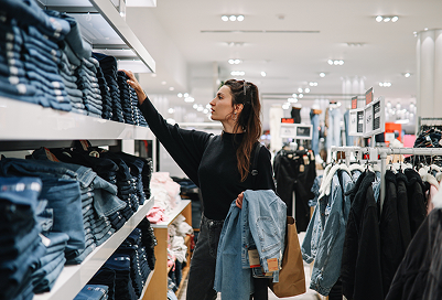 A woman looking at jeans on the shelf in a store